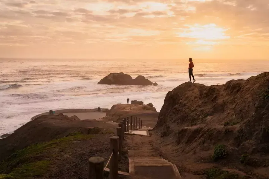 Duas pessoas estão em cima de pedras com vista para o oceano em Sutro Baths, em São Francisco.